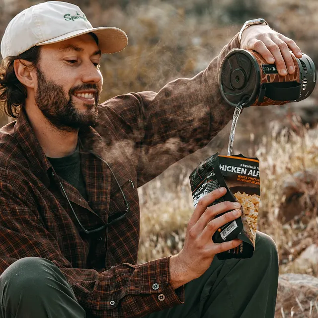 Pouring hot boiling water cooked in the Jetboil Zip 0.8L Fast Boil System in Duck camo into freeze dried meal to eat