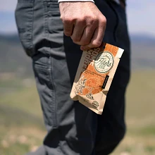 Close up of a Hikers Brew Some Mores trail coffee packet held by a man