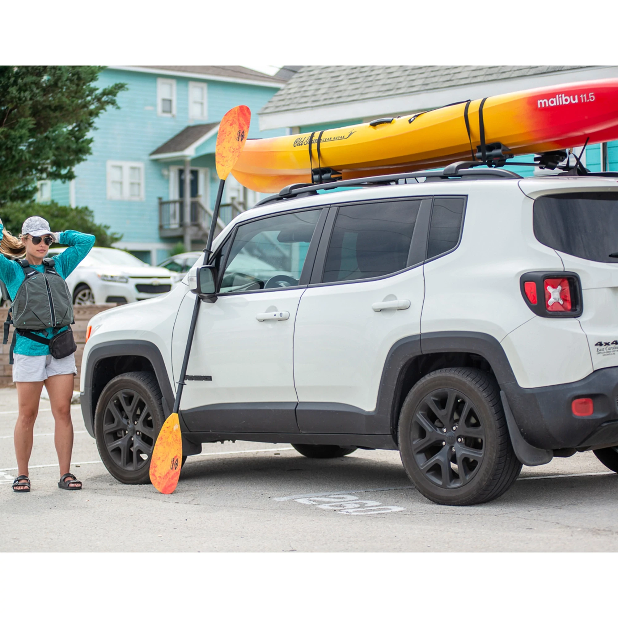 Woman standing next to truck loaded with the Old Town Ocean Kayak Malibu 11.5 kayak