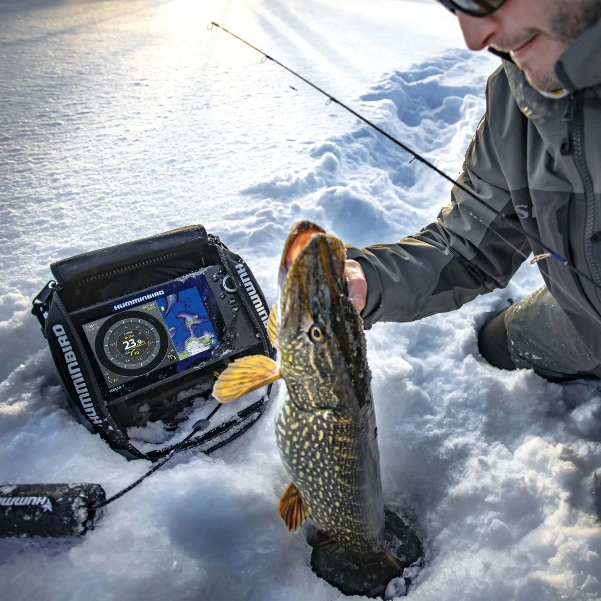 Ice angler pulling a large northern pike from a hole