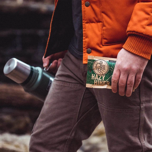 Man with Hikers Brew Hazy Hiker Trail Coffee packet and thermos