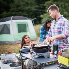 Camper cooking with the Gonzo Grill on the Eureka! Camp Kitchen table