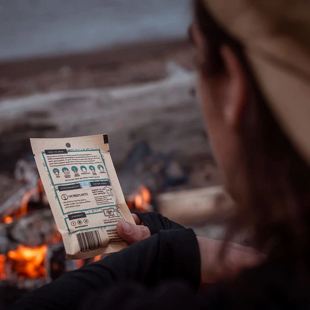 Camper reading the back of the coffee packet by the campfire