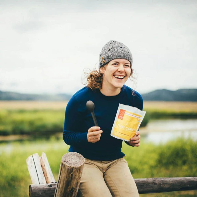 Woman sitting on fence with Good To-Go Thai Curry meal