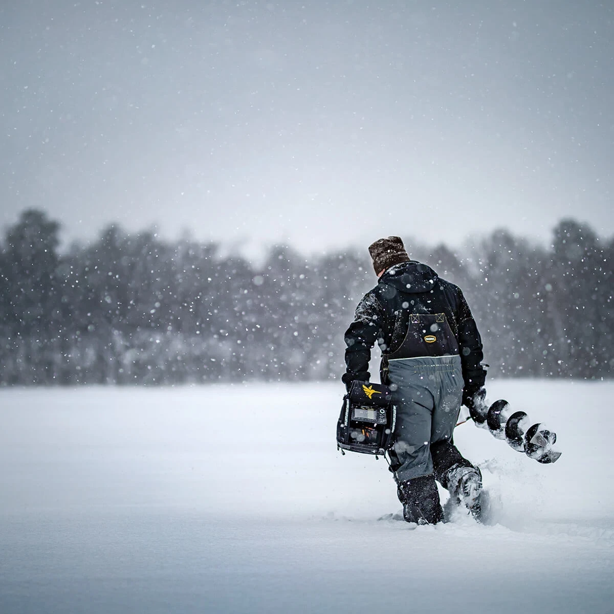 Angler carrying an ICE HELIX across a snowy lake