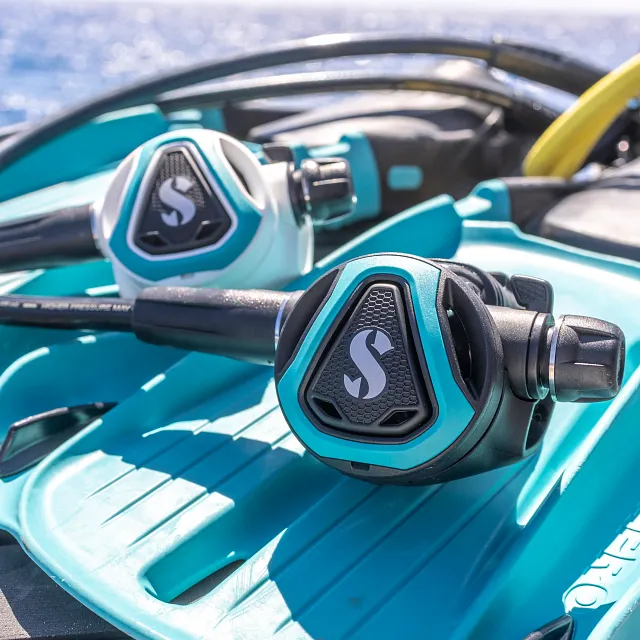 C370‑Tauchatemregler mit türkisfarbenem Farbrahmen auf türkis‑weißen Seawing‑Supernova‑Flossen neben dem Wasser.