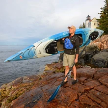 Man carrying Old Town Loon 120 kayak in cloud