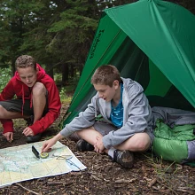 Boys sitting outside Timberline tent reading a map