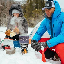 Man and Woman on a winter hike boiling water in MiniMo Cooking System